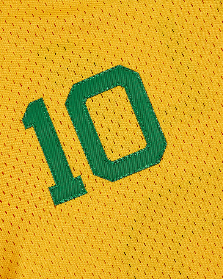 A close-up of the yellow Ebbets Field New York Cosmos Soccer Mesh Jersey with green number 10, featuring small perforations and visible stitching, iconic in American soccer history.
