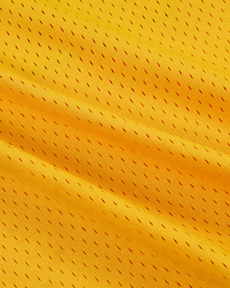 Close-up of yellow mesh fabric with small, evenly spaced holes and diagonal folds, inspired by the New York Cosmos Soccer Mesh Jersey from Ebbets Field.