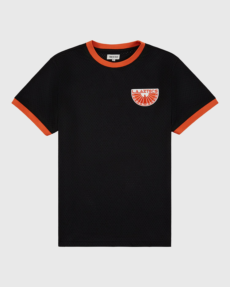 The Ebbets Field Los Angeles Aztecs Mesh Soccer Jersey is a black short-sleeve mesh top with orange trim on the collar and cuffs, and features an orange and red patch logo on the left chest, laid flat on a white background.