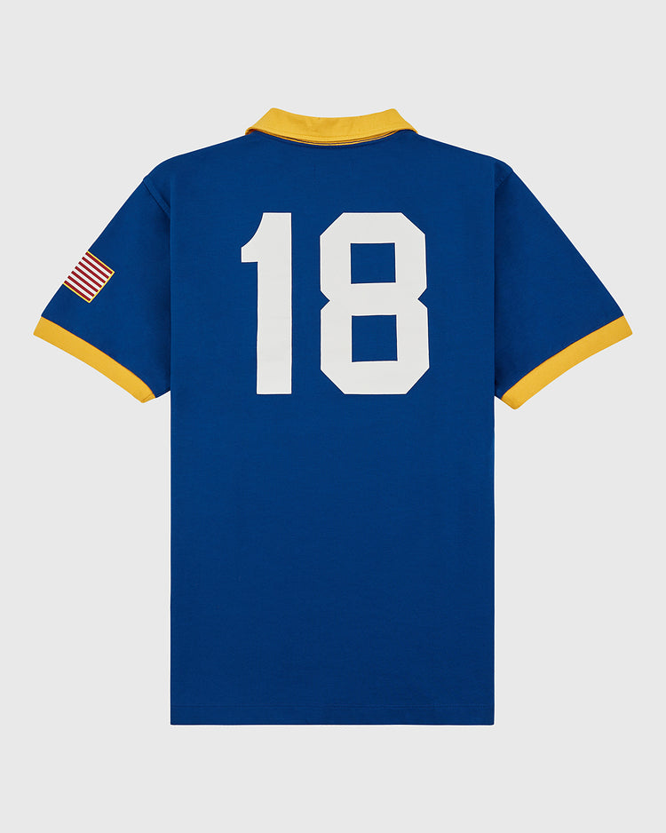 The Ebbets Field Pennsylvania Stoners Vintage Collar Soccer Jersey features a blue cotton build, yellow collar and cuffs, a large white number 18 on the back, an American flag patch on the sleeve, and retro-inspired screen printing.