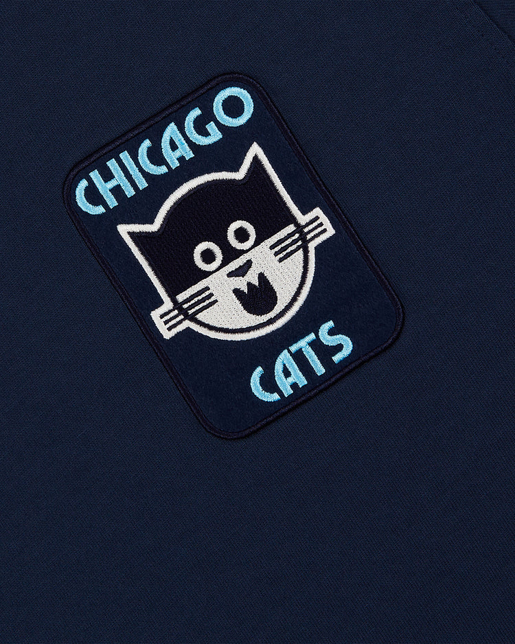 The Chicago Cats Vintage Collar Soccer Jersey by Ebbets Field is a navy cotton jersey with a cartoon black cat patch and “CHICAGO CATS” in light blue—ideal for fans of the classic American Soccer League team.