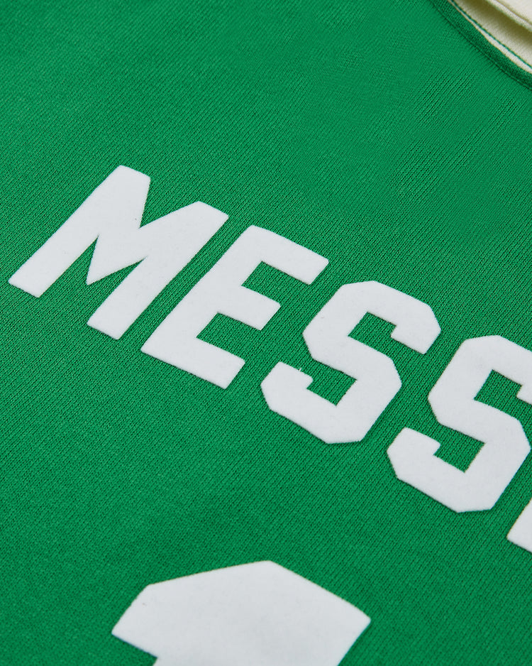 Close-up of a green New York Cosmos Vintage Soccer Goalie Jersey by Ebbets Field, featuring a collar, long sleeves, the name MESSI, and part of a white number below.