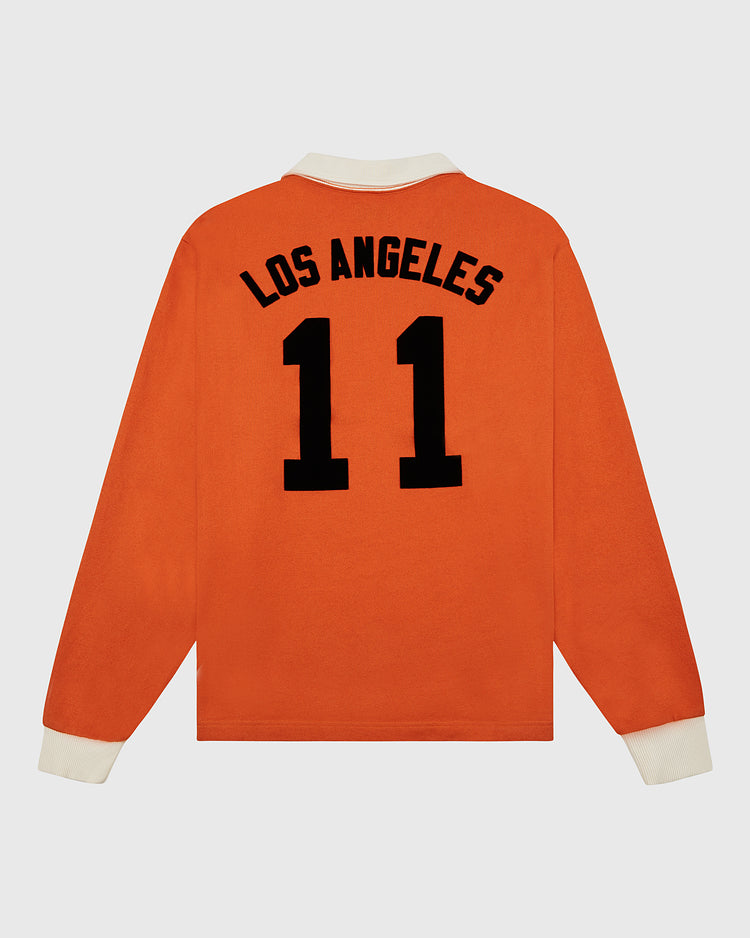 The Los Angeles Aztecs Vintage Soccer Goalie Jersey by Ebbets Field is an orange long-sleeve shirt with white cuffs and collar, inspired by an Aztecs jersey, featuring “LOS ANGELES” and the number 11 in bold black on the back.