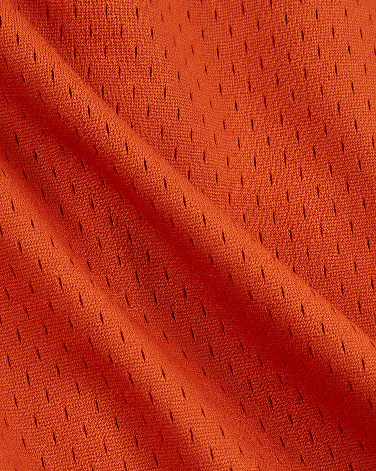 Close-up of orange athletic mesh with small, even holes and textured folds, highlighting the breathable, flexible material of the Ebbets Field Los Angeles Aztecs Mesh Soccer Shorts.