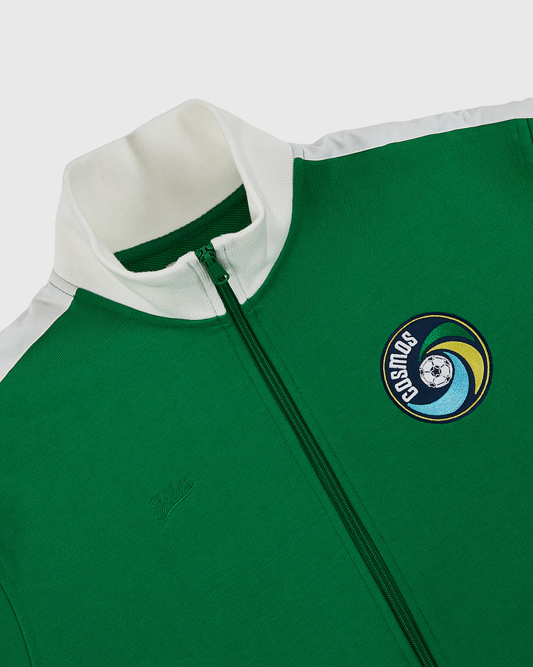 The Ebbets Field New York Cosmos Soccer Warm Up Jacket features a green zip design with white stand-up collar, shoulder stripes, and a Cosmos logo patch on the left chest—a tribute to Pelé’s legendary legacy.