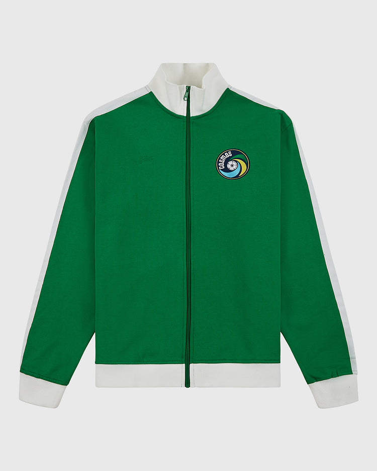 The Ebbets Field New York Cosmos Soccer Warm Up Jacket is green with white cuffs, collar, and shoulder stripes. It has a front zipper and a left chest patch featuring a soccer ball and “Cosmos,” inspired by Pelé’s legendary era.