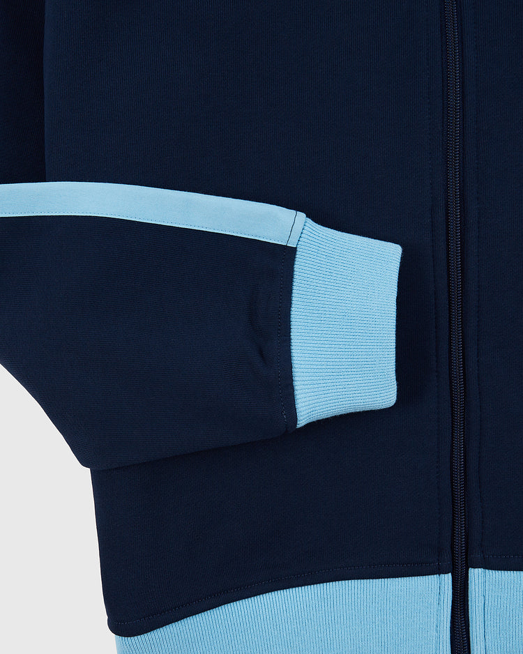 A close-up of the Ebbets Field Chicago Cats Soccer Warm Up Jacket sleeve shows its navy design with a light blue cuff, horizontal stripe, and vertical zipper—classic American Soccer League details.