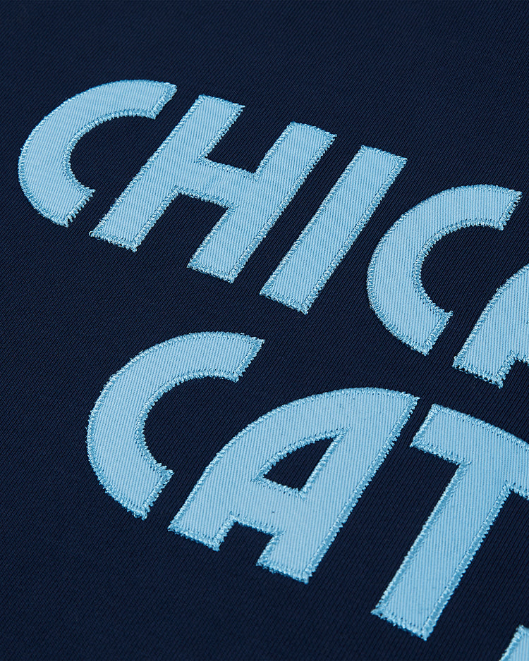 Close-up of light blue embroidered letters on a dark blue Ebbets Field Chicago Cats Soccer Warm Up Jacket, highlighting the detailed stitching and partially showing 