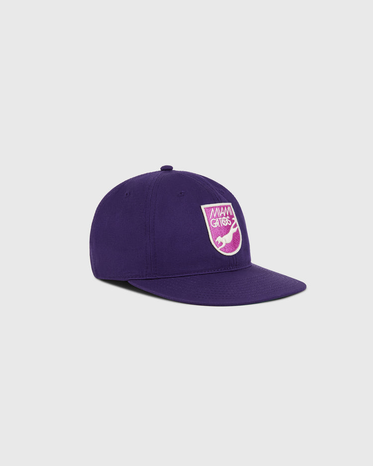 The Ebbets Field Miami Gatos Cotton Twill Ballcap features a purple design with a curved brim and a front pink-and-white patch honoring the Miami Gatos and NASL history. Displayed against a plain light background.