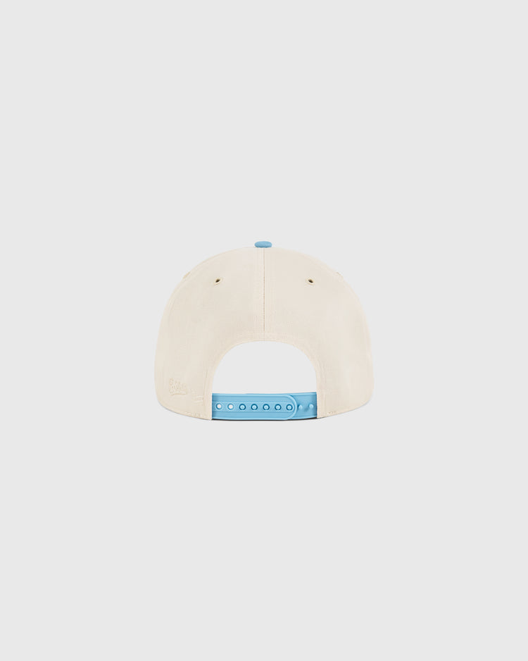 The Ebbets Field Dallas Tornados A-Frame Cotton Twill Ballcap is shown from the back, featuring a beige design with a light blue adjustable snap closure, displayed on a plain white background.