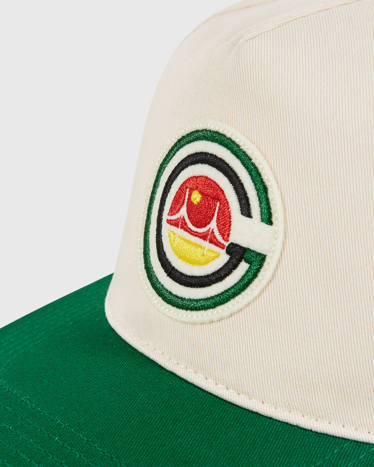 A close-up of the Ebbets Field San Francisco Golden Gate Gales A-Frame Cotton Twill Ballcap, featuring a white and green structure with an embroidered circular logo showing a red bridge and yellow-orange sunset inside the letter C.