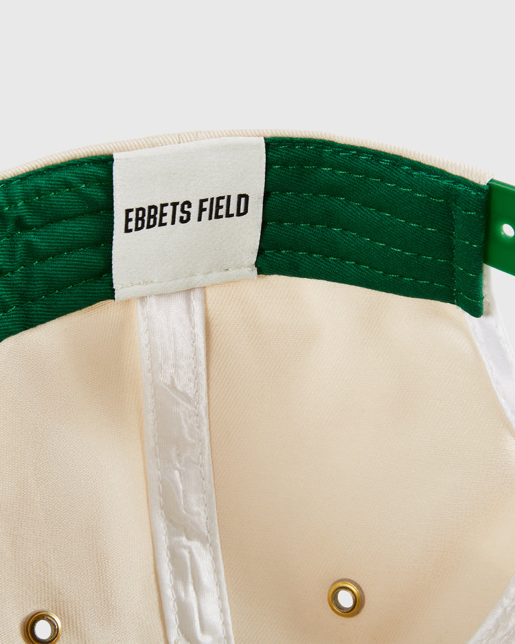 Close-up of the San Francisco Golden Gate Gales A-Frame Cotton Twill Ballcap by Ebbets Field, showing a white Ebbets Field label, green inner band, stitching details, gold ventilation holes, and cream-colored structured crown.