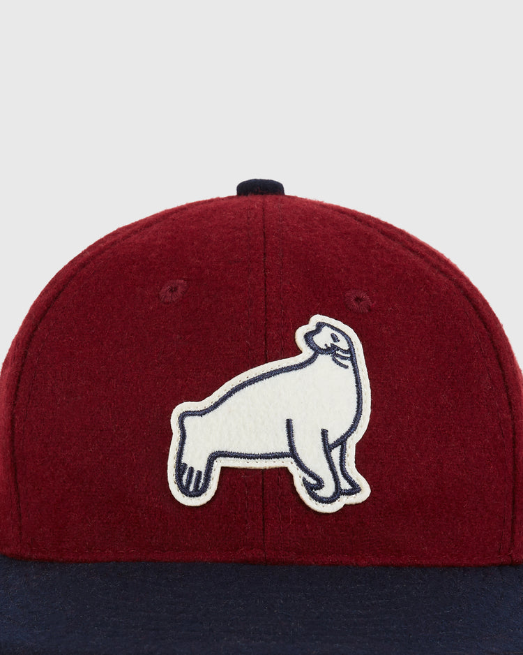 A close-up of the Ebbets Field San Francisco Seals 1940 Wool Ballcap, featuring a deep red crown, navy blue brim, and a white patch with a black-outlined seal on the front—paying tribute to Pacific Coast League history.