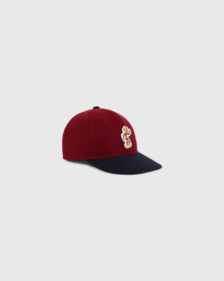 The Ebbets Field Red Reddy K 1940 Authentic Ballcap features a burgundy crown, navy blue brim, and an embroidered bear patch on the front, shown against a light gray background.