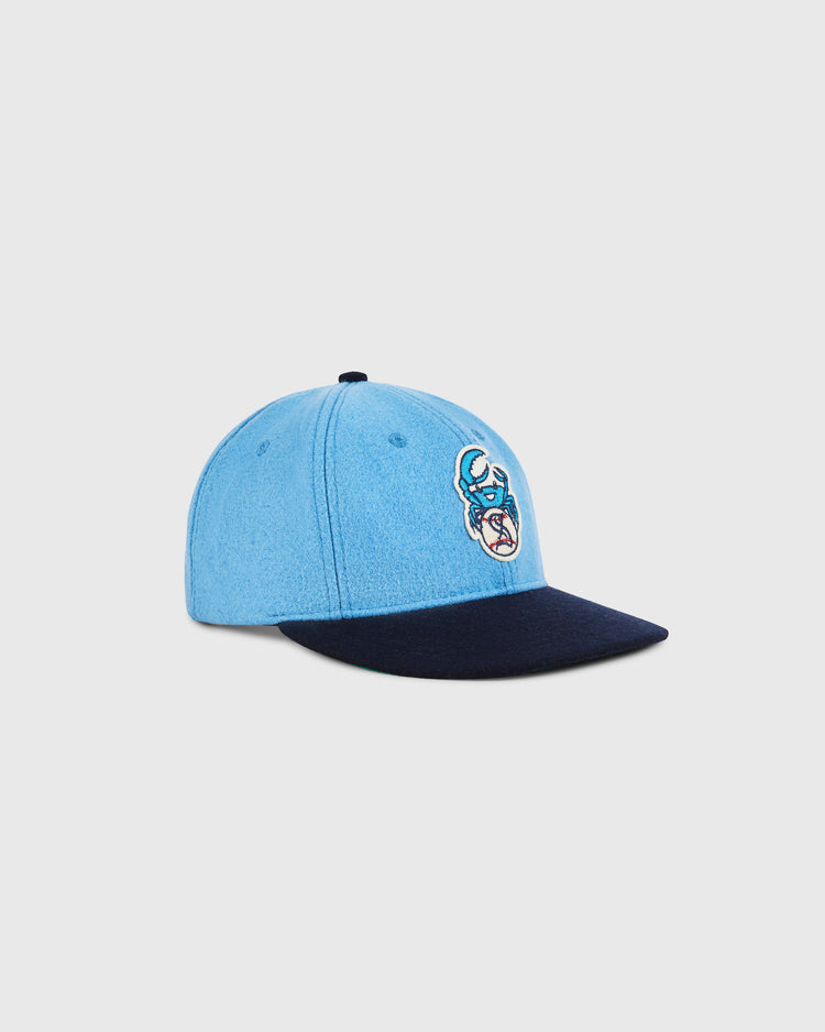 The Ebbets Field Santurce Cangrejeros Crab Wool Ballcap features a light blue crown, dark navy brim, and a vibrant embroidered crab inspired by Puerto Rican baseball, paying homage to classic wool ballcap style.