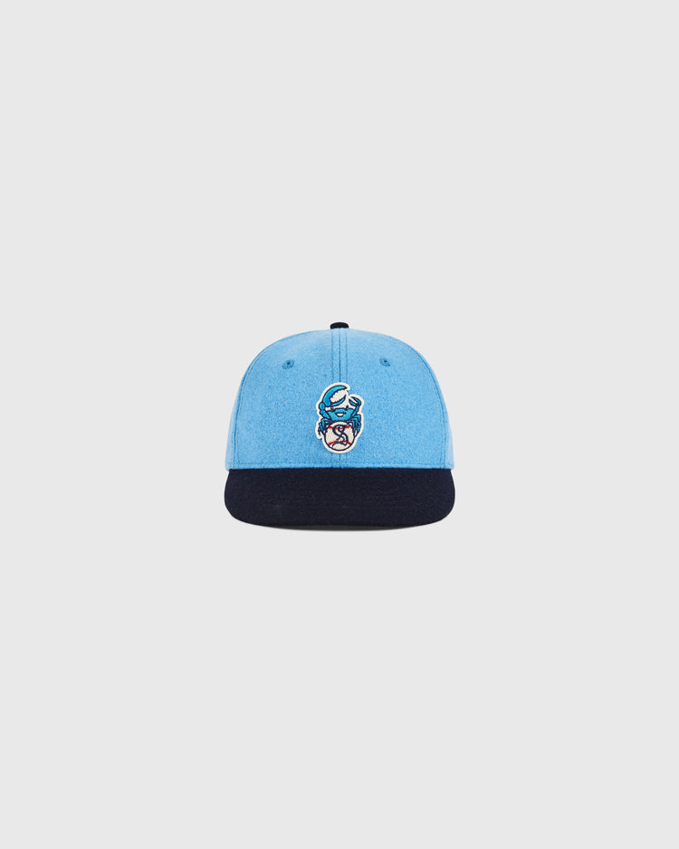 The Ebbets Field Santurce Cangrejeros Crab Wool Ballcap (Youth Size) is light blue with a dark blue brim and features an embroidered moon and stylized face logo, inspired by the legendary team, shown on a plain white background.