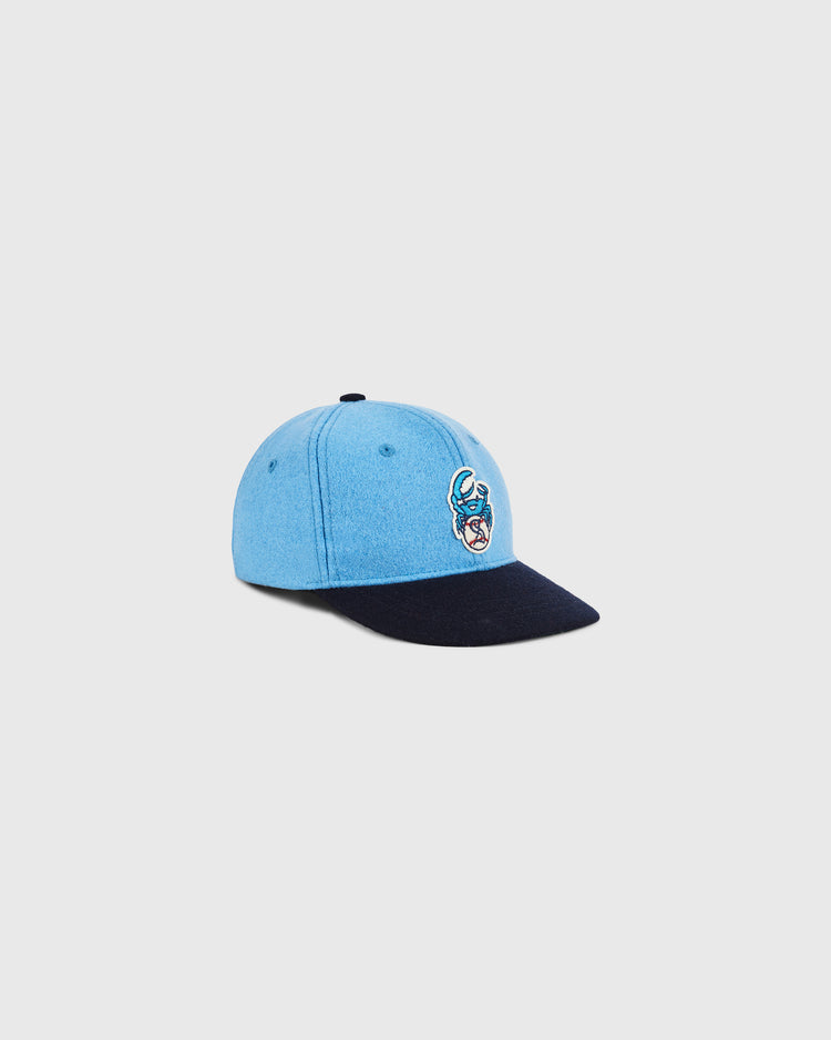 The Ebbets Field Santurce Cangrejeros Crab Wool Ballcap (Youth Size) features light blue wool, a dark navy brim, and an embroidered crab on the front. This Puerto Rican baseball cap is shown against a plain, light background.