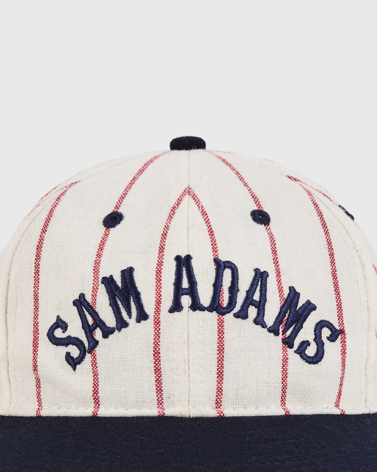 The Sam Adams Pinstripe Wool Ballcap by Ebbets Field features a cream color with thin red pinstripes, 