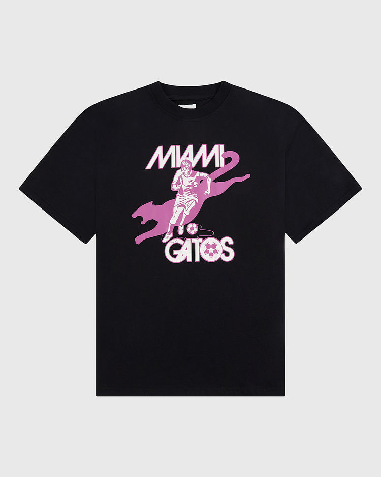 The Ebbets Field Miami Gatos Short Sleeve Graphic T-Shirt features a black base with a pink soccer player, large cat, and ball graphic, plus bold vintage 