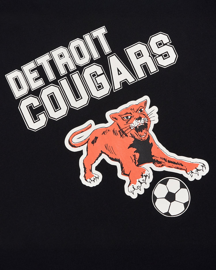 The Detroit Cougars Short Sleeve Graphic T-Shirt by Ebbets Field features a bold orange cougar pouncing over a soccer ball with 