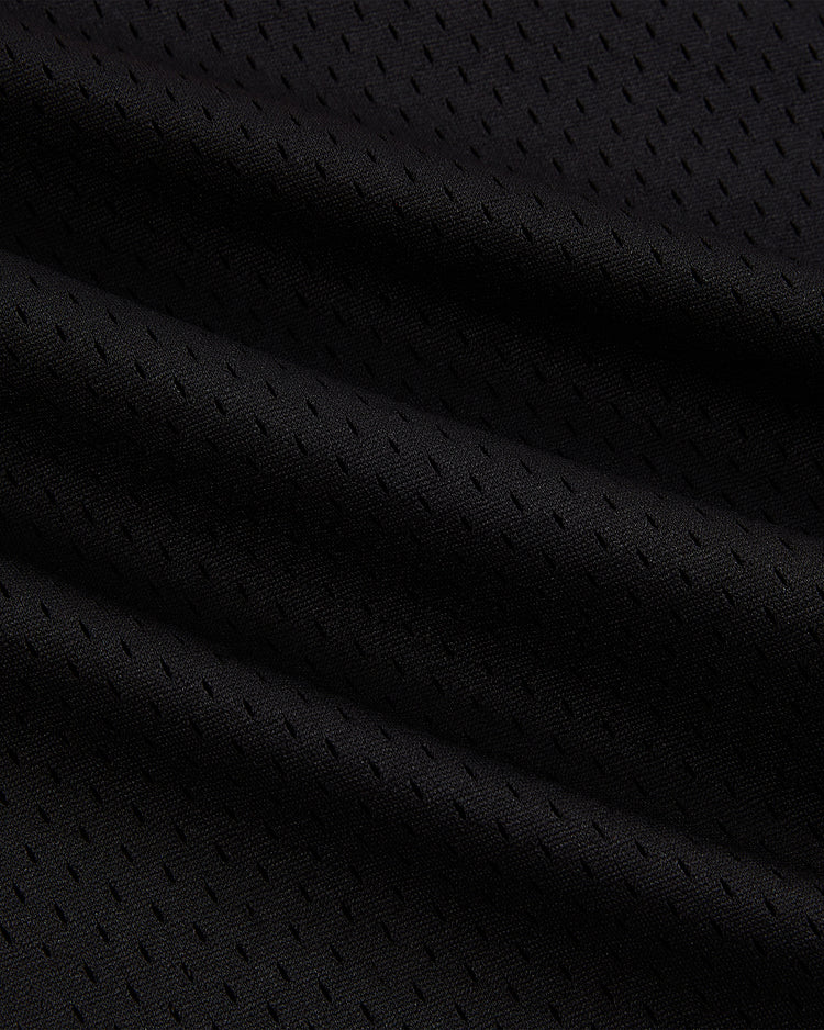 Close-up of Detroit Cougars Mesh Soccer Jersey by Ebbets Field, featuring black mesh fabric with small perforated holes and visible folds, showcasing its vintage-inspired breathable texture.