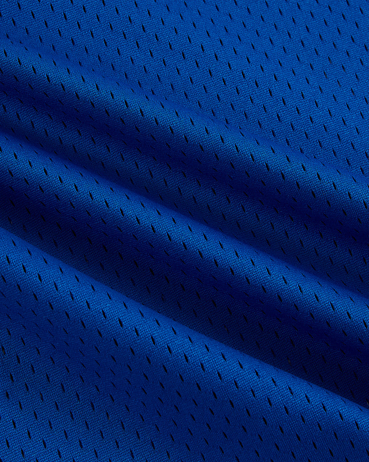 Close-up of the Ebbets Field New Jersey Americans Mesh Soccer Jersey in blue, featuring small black perforations, a textured surface, and slight folds.