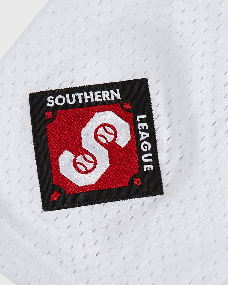 A close-up of the white mesh fabric on the Ebbets Field Birmingham Barons Frank Thomas Button Up Mesh Jersey, showcasing a rectangular SOUTHERN LEAGUE patch with two overlapping baseballs in a red and black geometric design—evoking classic Birmingham Barons and Frank Thomas jersey details.