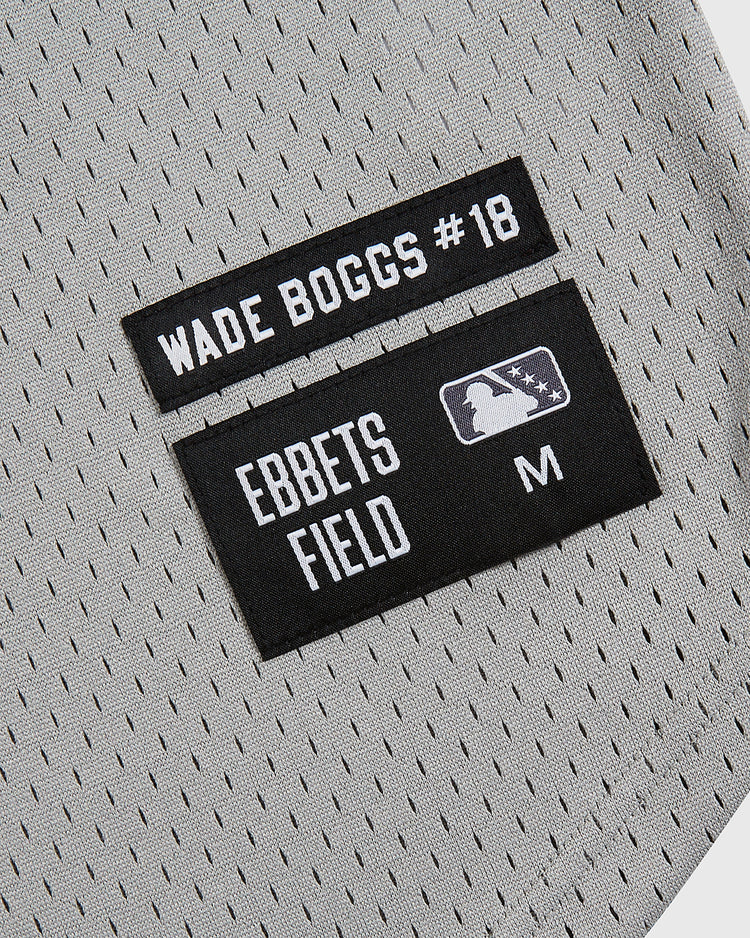 Close-up of two black fabric labels on a gray mesh v-neck jersey. One reads 