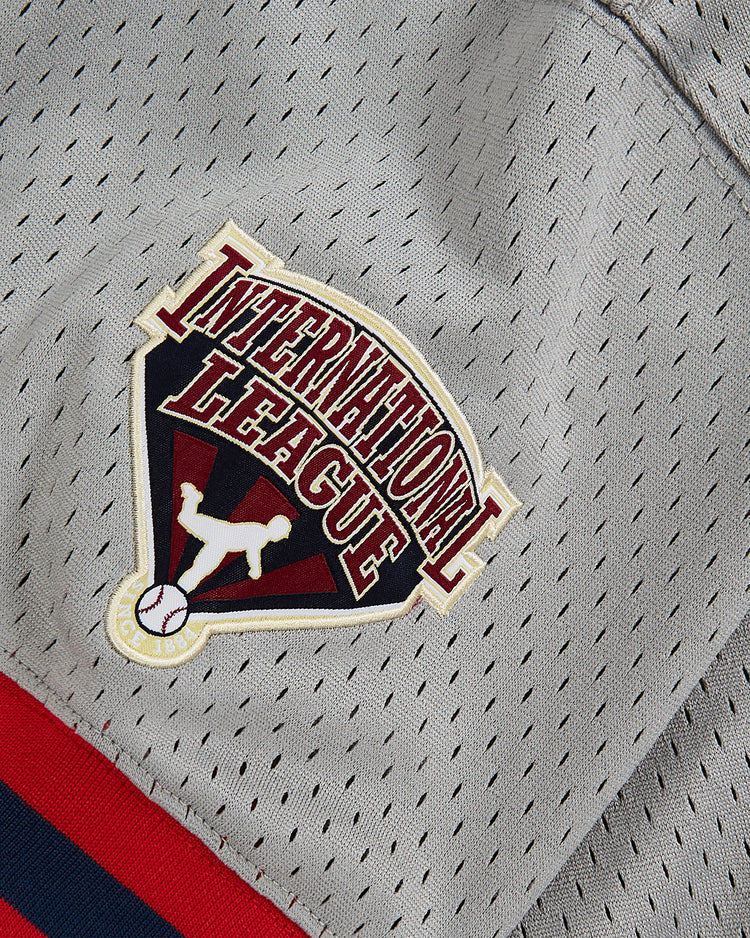 Close-up of the Wade Boggs Pawtucket Red Sox Mesh V-Neck Jersey by Ebbets Field, featuring gray mesh fabric and an International League patch with a baseball player silhouette above a small baseball—echoing the classic style worn by the Pawtucket Red Sox and legends like Wade Boggs.