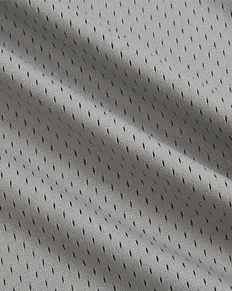 Close-up of light gray athletic mesh fabric featuring small, evenly spaced black ventilation holes that create a textured, breathable look—reminiscent of the classic Ebbets Field Wade Boggs Pawtucket Red Sox Mesh V-Neck Jersey.