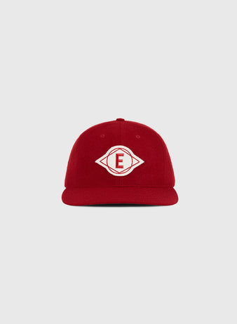An Escogido Leones 1955 Authentic Wool Ballcap by Ebbets Field, in red wool with a white embroidered diamond-shaped logo featuring the letter “E” in the center, displayed on a plain light gray background.