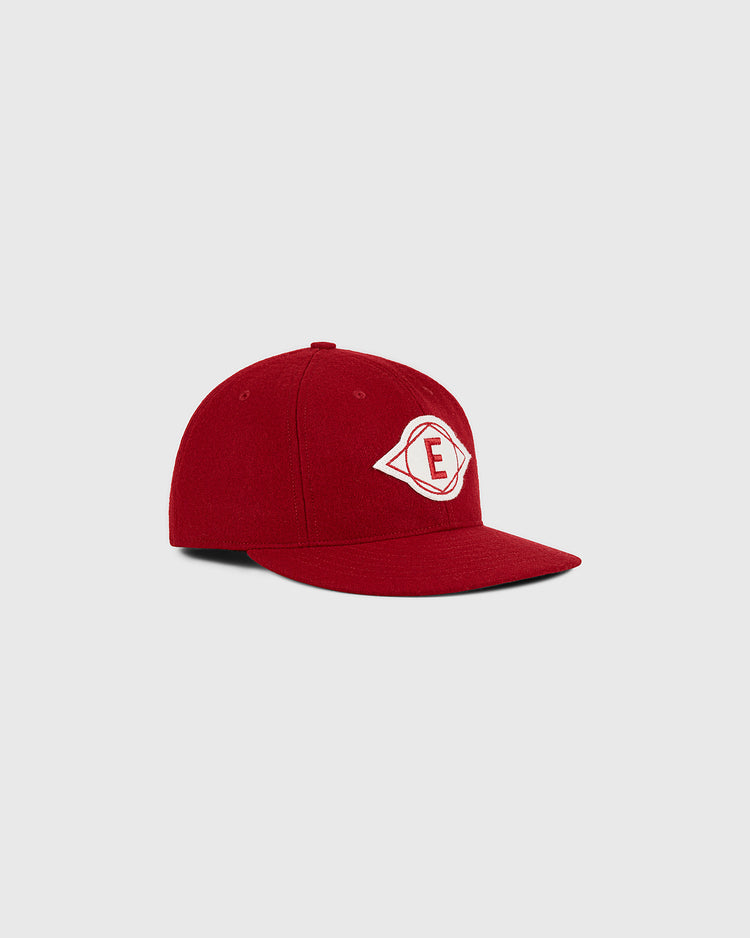 The Escogido Leones 1955 Authentic Wool Ballcap by Ebbets Field, a red baseball cap featuring a white patch with a red letter E inside a diamond shape on the front, is displayed against a light gray background.