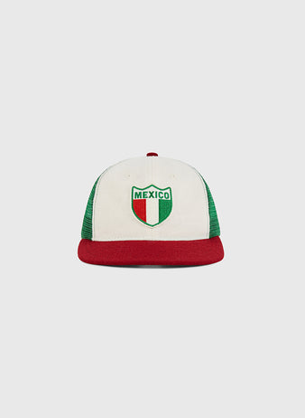 The Ebbets Field Mexico Wool Mesh Trucker Ballcap features a white and green design with a red brim and a Mexico crest on the front in green, white, and red—the colors of the Mexican flag.