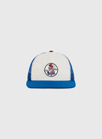 An Ebbets Field Nashville Sounds Mesh Trucker Ballcap in white and blue, featuring a red button on top and a circular baseball-themed patch with a red cardinal on the front, displayed against a plain light gray background.
