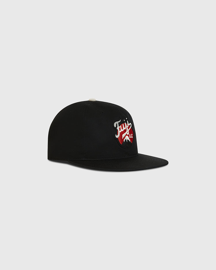 The Ebbets Field Fuji Athletic Club Cotton Twill Ballcap is crafted from black cotton twill and features a flat brim. The front showcases a red and white embroidered “Fuj” logo with a wavy underline, paying tribute to Japanese American baseball heritage and the iconic Fuji Athletic Club. The cap is photographed against a plain light gray background.