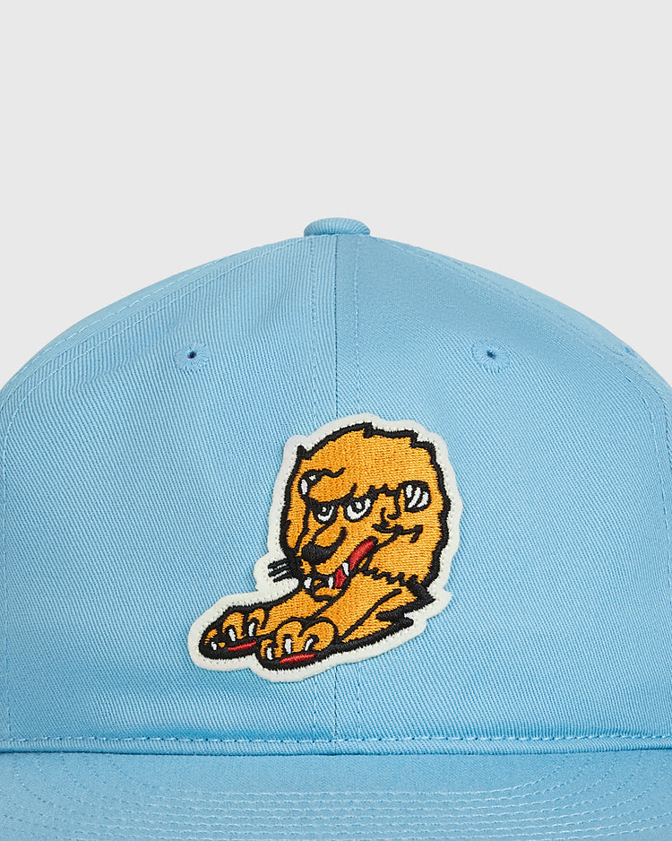 The Ebbets Field Nishitetsu Lions 1971 Cotton Twill Ballcap is a light blue vintage-style cap featuring a patch of a cartoonish, orange furry creature holding a red object stitched on the front.