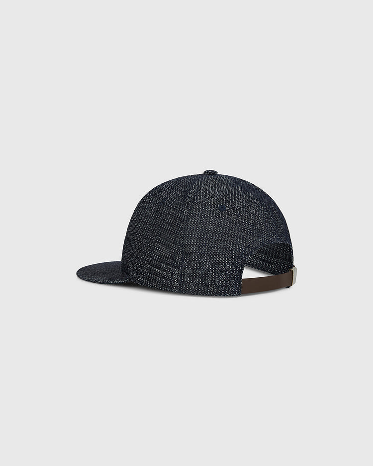 The Sankei Atoms Japanese Indigo Cotton Dobby Ballcap by Ebbets Field is shown from the back and side, highlighting its deep indigo hue, textured dobby cotton finish, and curved brim. Inspired by Japanese baseball history, the cap features an adjustable brown strap with a metal clasp. The background is a plain light gray.