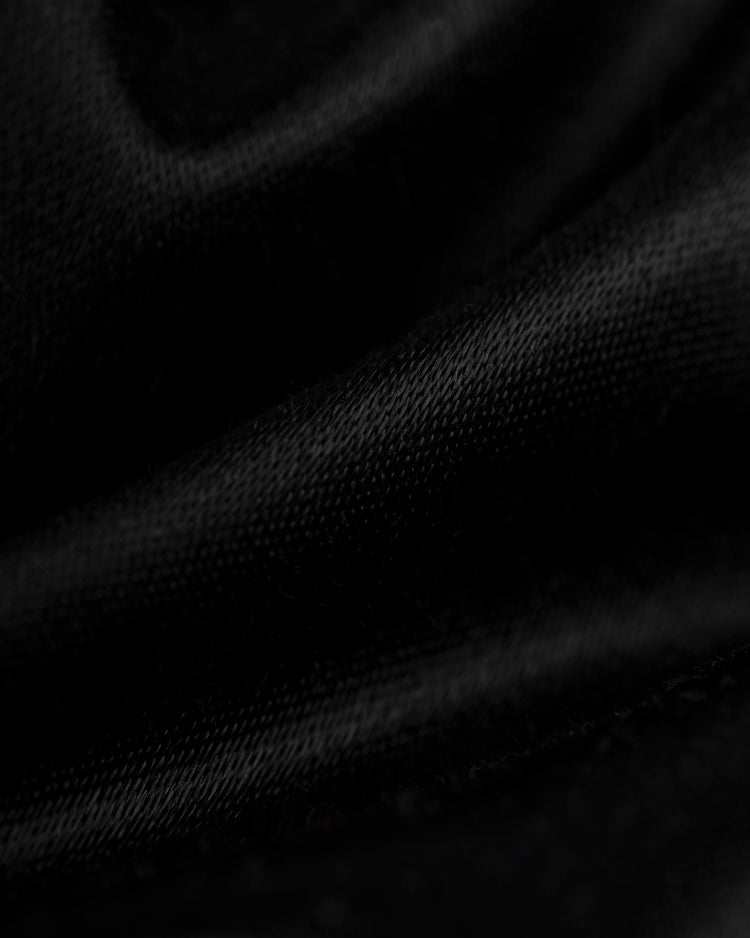 Close-up of soft black fabric with gentle folds and sheen, just like the material in the EFF Milwaukee Braves 1957 Authentic All Satin Varsity Jacket. Subtle shadows and highlights evoke classic vintage style.