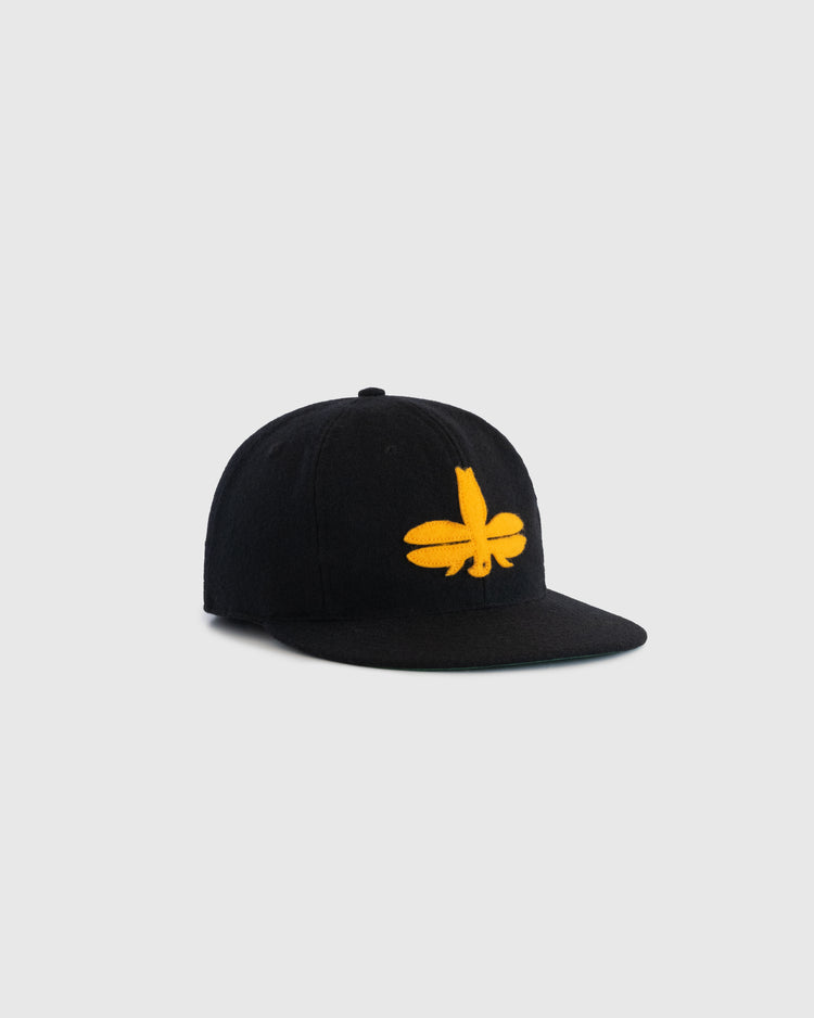 The EFF Tombow Unions 1955 Authentic Wool Ballcap is a black cap with a bold yellow embroidered flower or Dragonfly logo on the front, inspired by Japanese baseball history, displayed on a plain light gray background.
