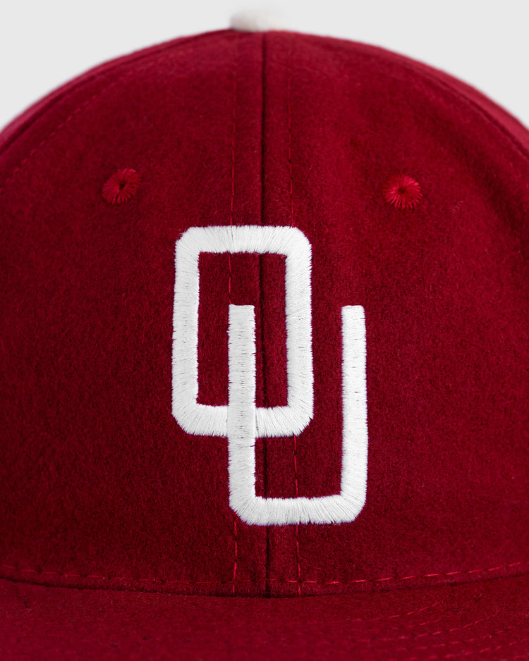 A close-up of the EFF University of Oklahoma 1975 Authentic Wool Ballcap, featuring a red cap with the white embroidered interlocking OU logo, inspired by the classic cap worn during the Sooners’ College World Series run.