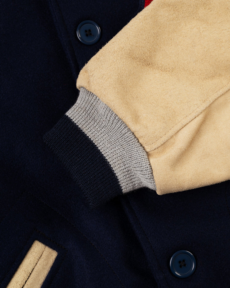 Close-up of the EFF Boston Red Sox 1938 Authentic Wool & Suede Leather Varsity Jacket sleeve, featuring tan suede, gray and black ribbed cuff, navy buttons, and a navy body with tan pocket trim inspired by the classic letterman style.