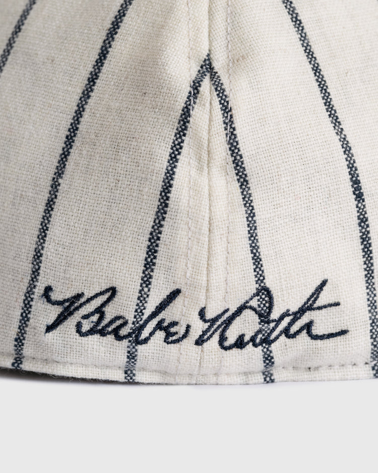 A cream-colored Babe Ruth 1932 Signature Series Wool Ballcap by Ebbets Field Flannels, detailed with thin black stripes and Babe Ruth’s embroidered signature—an ideal piece for baseball memorabilia enthusiasts.