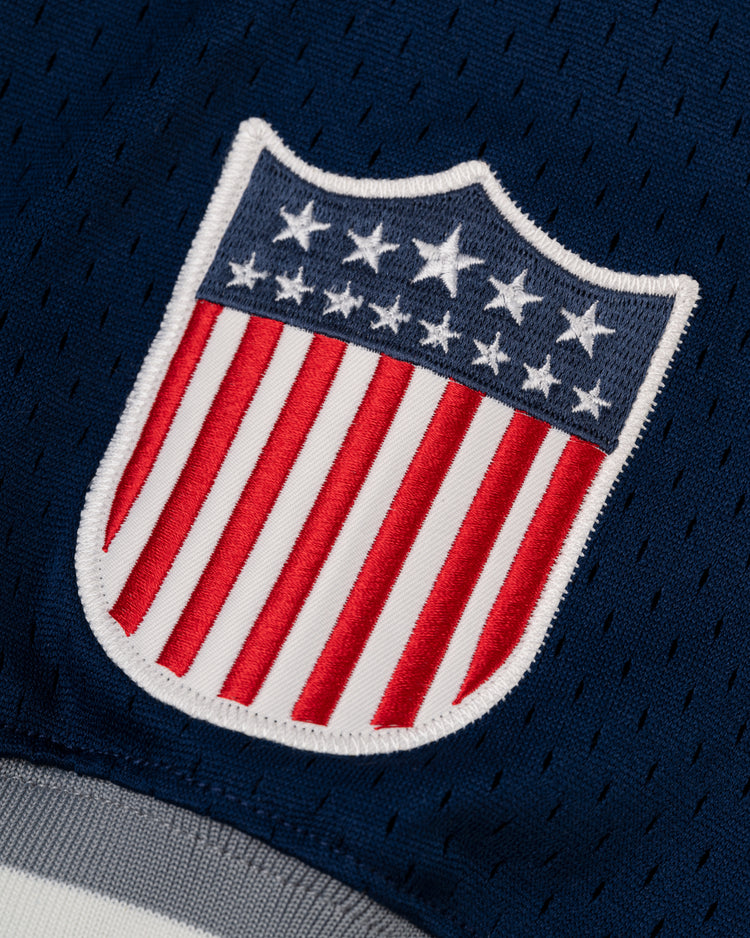 Close-up of a USA shield patch with white stars on blue and red/white stripes, stitched onto the EFF Homestead Grays Mesh V-Neck Jersey—an homage to baseball history.