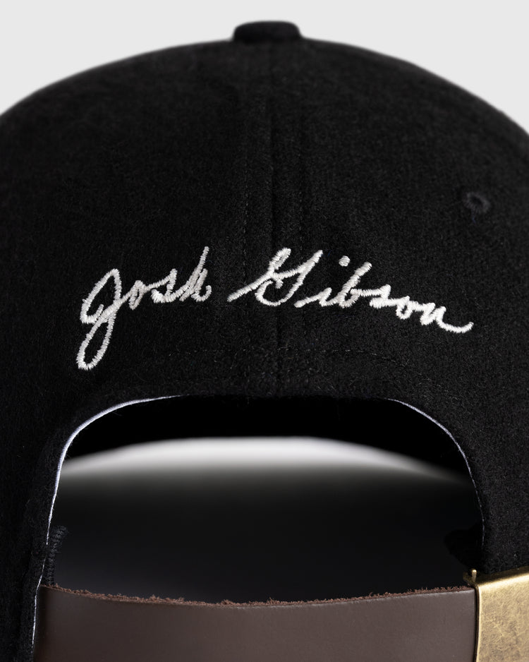 Close-up of the Ebbets Field Flannels Josh Gibson 1945 Signature Series Wool Ballcap, featuring white Josh Gibson script above an adjustable brown strap with a gold buckle—a tribute to Negro Leagues legends.