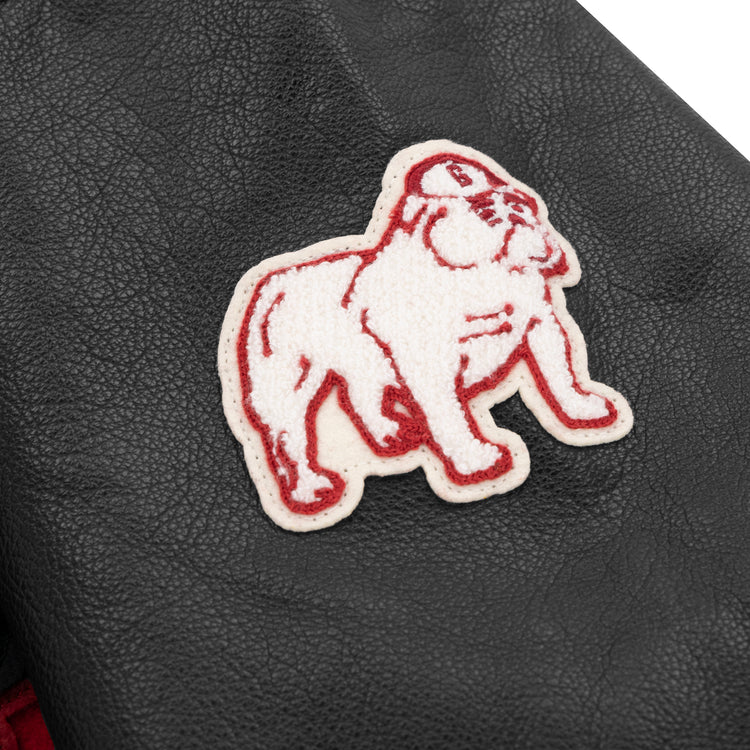 A white and red bulldog patch with a cap is sewn onto black leather, capturing the classic spirit of the EFF University of Georgia 1939 Authentic Jacket.