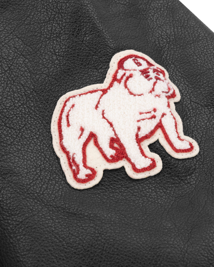 A white and red bulldog patch with a cap is sewn onto black leather, capturing the classic spirit of the EFF University of Georgia 1939 Authentic Jacket.