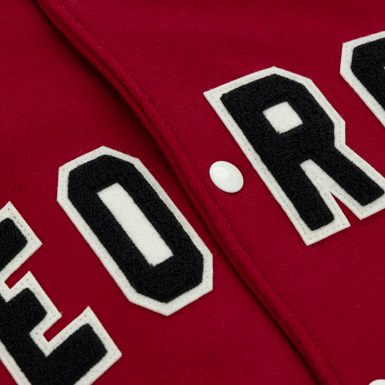 Close-up of red fabric with bold white and black block letters and a white button on the EFF University of Georgia 1966 Authentic Jacket.