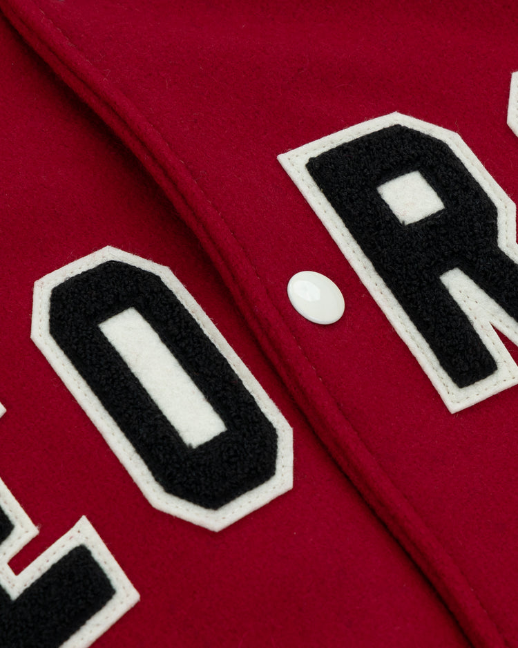 Close-up of red fabric with bold white and black block letters and a white button on the EFF University of Georgia 1966 Authentic Jacket.