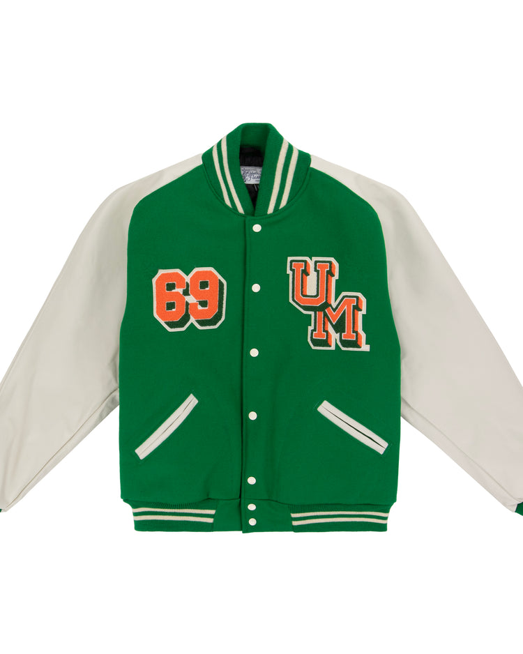 The EFF University of Miami 1969 Authentic Jacket features green body, white sleeves, striped cuffs and collar, snap buttons, and orange “69” and UM patches on the chest—perfect for a classic Miami varsity look.