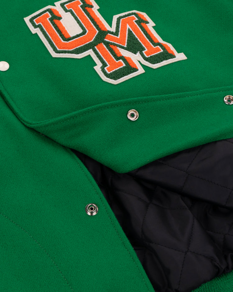 Close-up of the EFF University of Miami 1969 Authentic Jacket, featuring a green exterior, quilted black lining, metal snap buttons, and an orange and white UM chest patch.